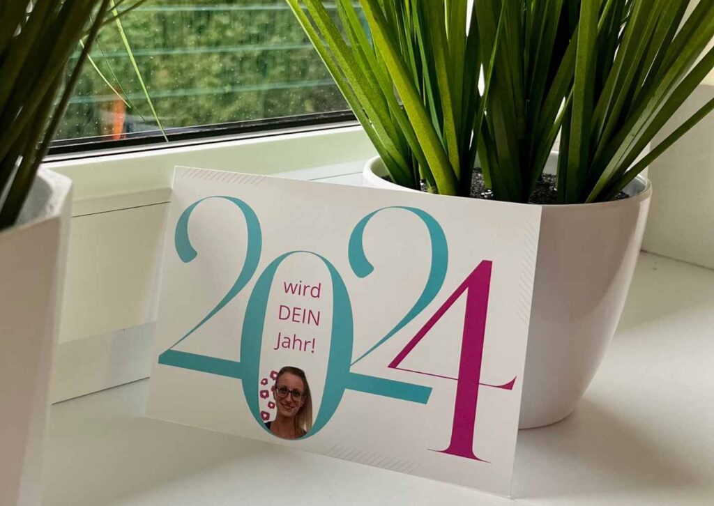 Martina schreibt jedes Jahr an alle ihre Kund:innen Neujahrsgrüße per Hand. Auf per eigens mit Canva gestalteten Postkarte aus 2024 steht "2024 wird dein Jahr", dabei ist Martinas Profilfoto in die 0 von 2024 eingearbeitet.